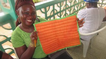 A Woman's Club member holds up a patchwork square