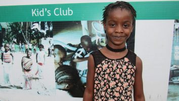 A little girl poses in front of a poster at Mineke Foundation